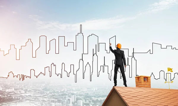 エンジニアの男が家の屋根の上に立って街を描く 混合メディア — ストック写真