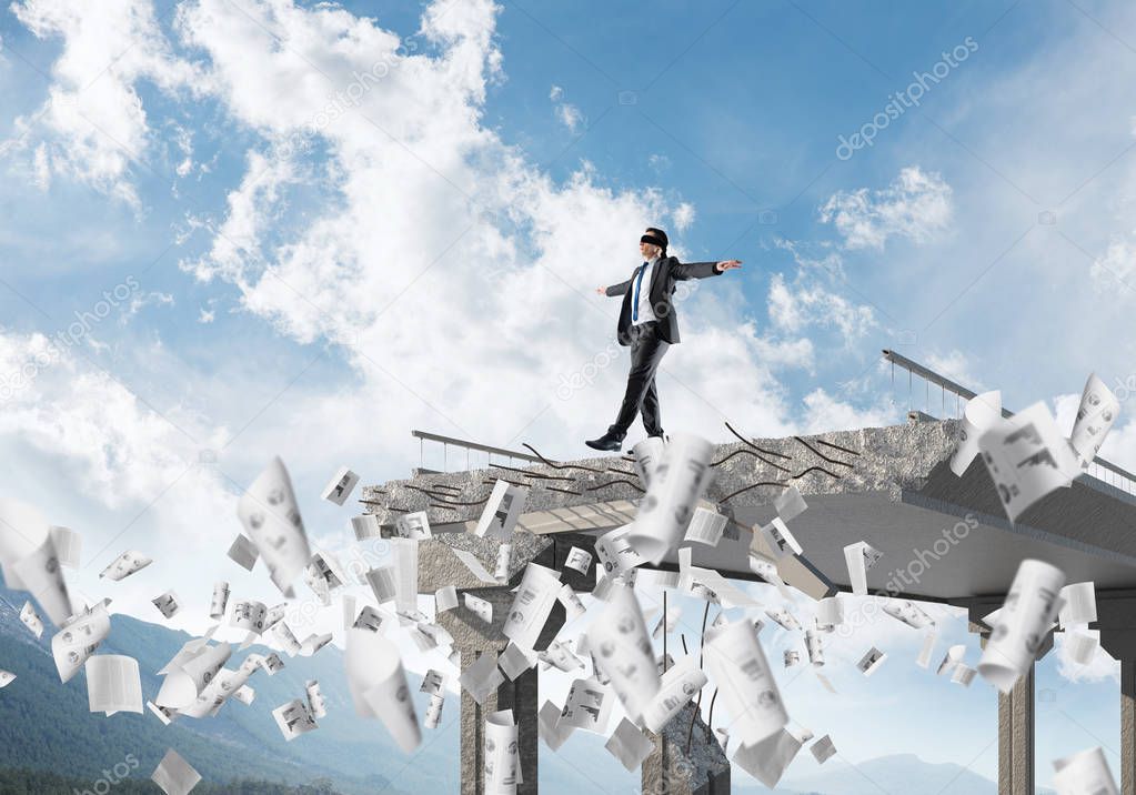 Businessman walking blindfolded among flying documents on concrete bridge with huge gap as symbol of hidden threats and risks. Skyscape and nature view on background. 3D rendering.