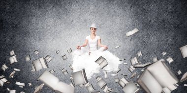 Kadın beyaz giyim gözler tutmak kapalı ve seyir üzerinde uçan bulut kitaplar ile gri karanlık duvar arka plan üzerinde uçan arasında meditasyon sırasında konsantre.