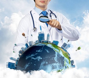Kavramsal görüntü içinde beyaz Tıbbi üniforma Büyüteç aracılığıyla dünya dünya üzerinde arka plan üzerinde bulutlu gökyüzü ile seyir emin doktor. Tıp sektöründe kavramı. Nasa tarafından döşenmiş bu görüntü unsurları