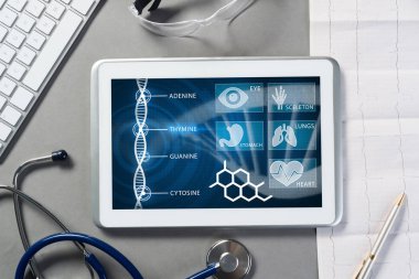 Gri yüzeyde beyaz tablet ve doktor araçları