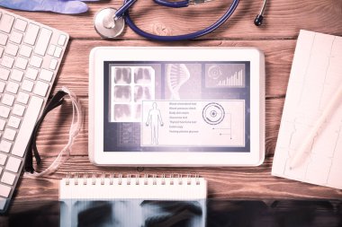 Beyaz tablet bilgisayar ve doktor aletleri ahşap masada.