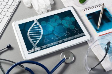 Gri yüzeyde beyaz tablet ve doktor araçları