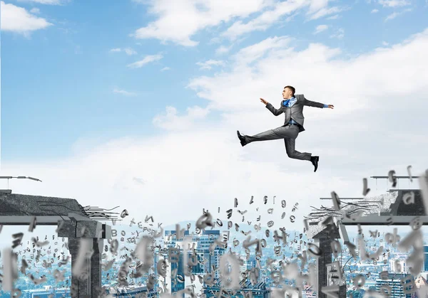 Businessman jumping over gap with flying letters in concrete bridge as symbol of overcoming challenges. Cityscape on background. 3D rendering.