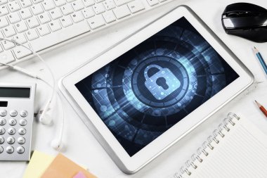 Ofis eşyalarıyla iş yeri ve ekranda asma kilit simgesi olan tablet
