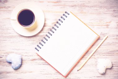 Kahve fincanı not defteri kalem ve ahşap yüzeyde iki kalp
