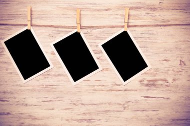 Boş fotoğraf çerçevesi ahşap bir zeminde ipte asılı.