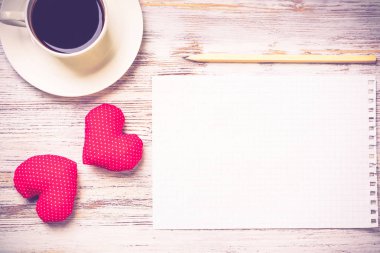 Kahve fincanı not defteri kalem ve ahşap yüzeyde iki kırmızı kalp