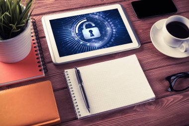 Ofis eşyalarıyla iş yeri ve ekranda asma kilit simgeleri olan tablet