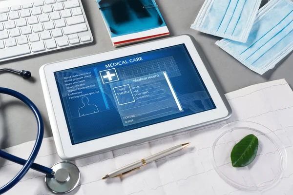 灰面上的白色平板电脑和医生工具 — 图库照片
