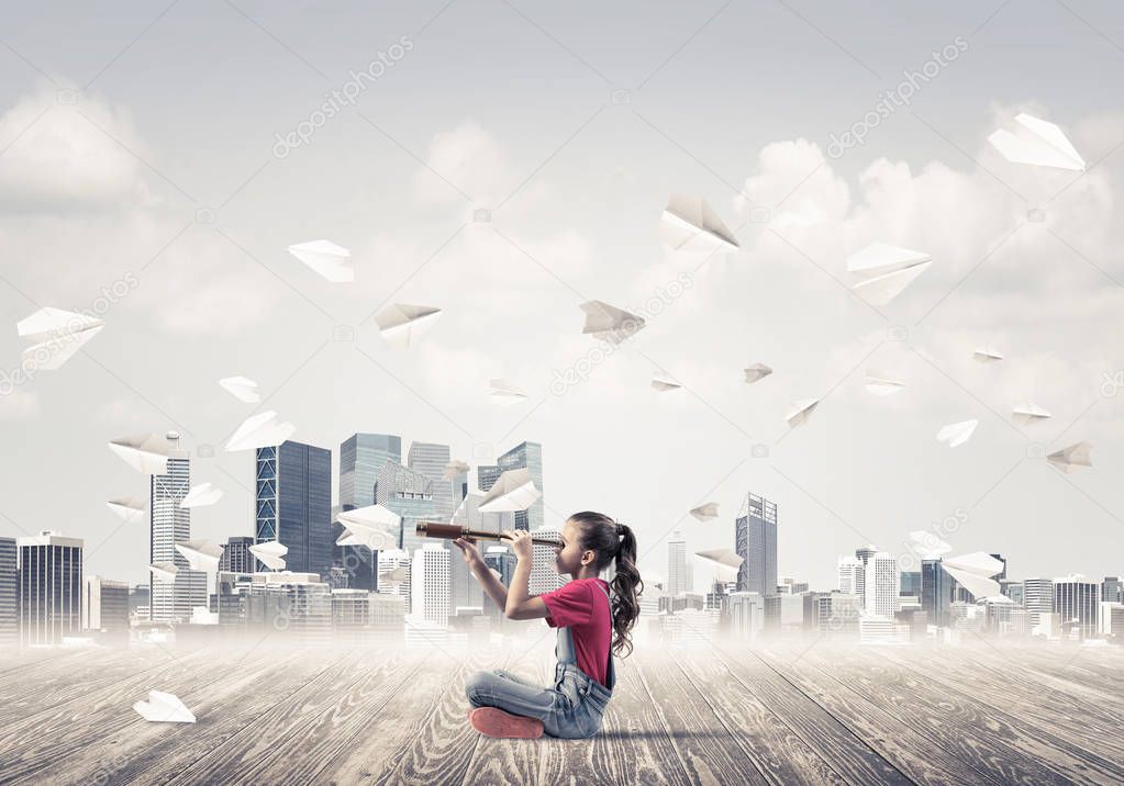 Cute kid girl sitting on wooden floor and paper planes flying around