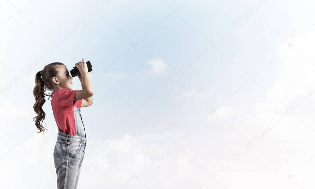 Little cute girl in overalls against sky background dreaming about future