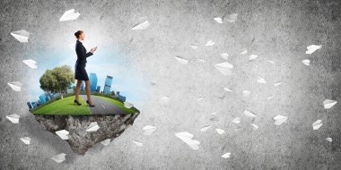 Yeşil yüzen adada beton zemine karşı duran kendine güvenen zarif bir iş kadını.