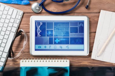 Beyaz tablet bilgisayar ve doktor aletleri ahşap masada.