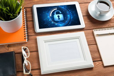 Ofis eşyalarıyla iş yeri ve ekranda asma kilit simgeleri olan tablet