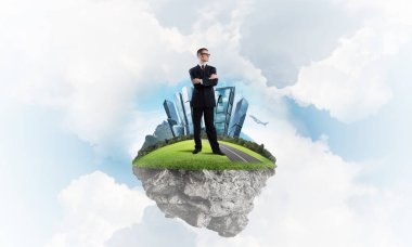 Mavi gök yeşil yüzen ada üzerinde duran zarif emin iş adamı