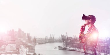 Sanal gerçeklik kulaklığı olan genç bir adam ya da şehrin arka planında 3 boyutlu gözlüklü.