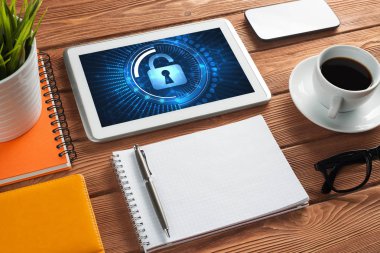 Ofis eşyalarıyla iş yeri ve ekranda asma kilit simgeleri olan tablet