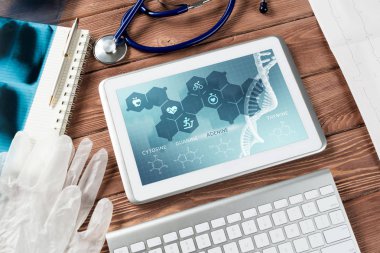 Beyaz tablet bilgisayar ve doktor aletleri ahşap masada.