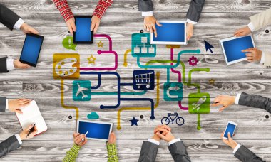 Ellerinde cihazlar bulunan bir grup insan, iletişim ve ağın sembolü olarak birlikte çalışıyor.