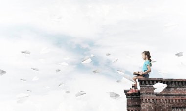 Çatı ve kitap okumak binasında oturan sevimli kız