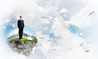 Mavi gök yeşil yüzen ada üzerinde duran zarif emin iş adamı