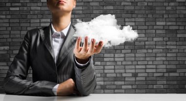 İş kadını closeup uygun arka plan üzerinde koyu tuğla duvar ile onun elinde sunan beyaz bulut. 