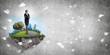 Yeşil yüzen adada beton zemine karşı duran kendine güvenen zarif bir iş kadını.