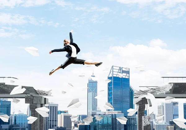 ビジネスの女性の課題を克服するためのシンボルとしてコンクリート橋で紙飛行機を飛行とのギャップを飛び越えます 背景の街並み レンダリング — ストック写真