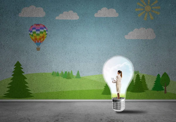 Businesswoman inside light bulb in room against nature drawn concept