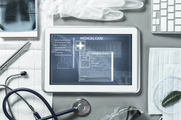 White tablet pc and doctor tools on gray surface