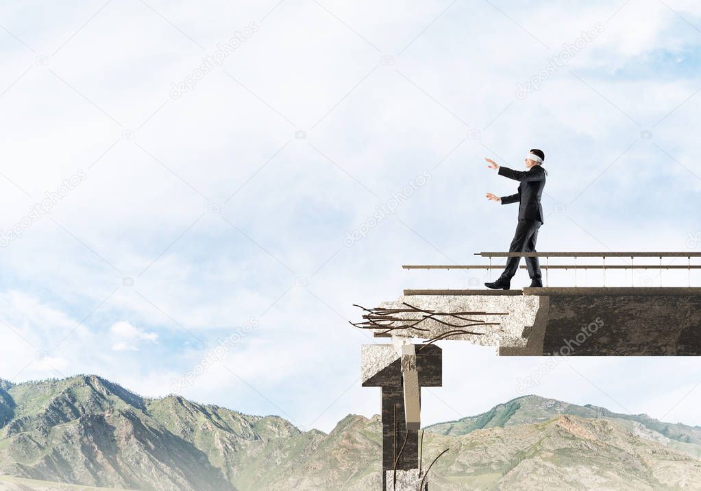 Businessman walking blindfolded on concrete bridge with huge gap as symbol of hidden threats and risks. Skyscape and nature view on background. 3D rendering.