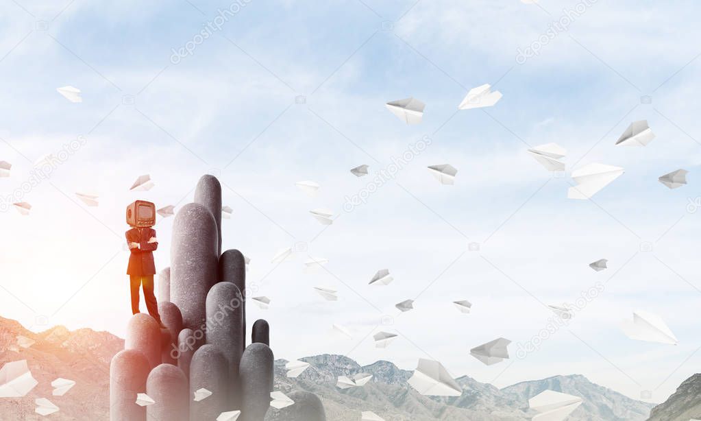 Businessman in suit with an old TV instead of head keeping arms crossed while standing on the top of stone columns among flying paper planes with beautiful landscape on background. 3D rendering.