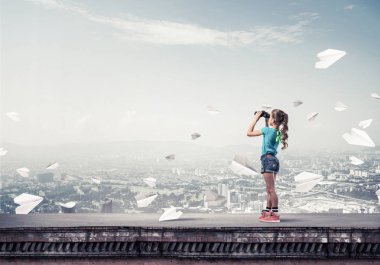 Dürbünle bakan, okul çağındaki sevimli kız çatıyı inşa ediyor.