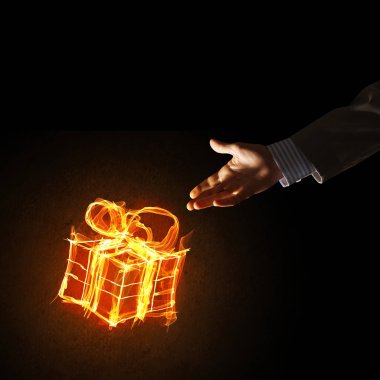 Parlayan yangın hediye kutusu simgesinin koyu arka plan üzerine gösteren işadamı ele