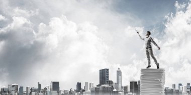 Rahat kıyafet ile cityscape arka plan üzerinde belgeleri yığını üzerinde dururken el kitabı ile uydurarak adam. Karışık teknik.