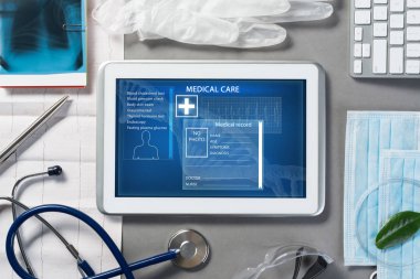 Gri yüzeyde beyaz tablet ve doktor araçları