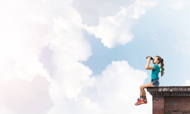 Dürbünle bakan, okul çağındaki sevimli kız çatıyı inşa ediyor.