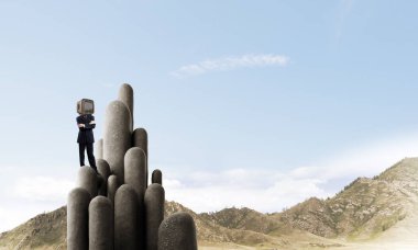 İşadamı kafasına silah tutmak yerine eski bir Tv ile takım elbiseli güzel manzara ile taş sütunlar tepesinde dururken arka plan üzerinde çarpı işareti.