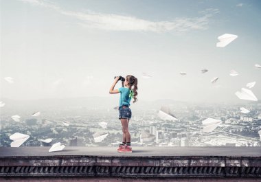 Dürbünle bakan, okul çağındaki sevimli kız çatıyı inşa ediyor.