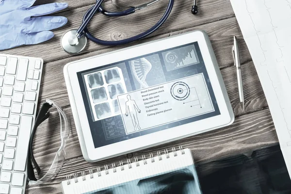 White tablet pc and doctor tools on wooden table