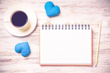 Kahve fincanı not defteri kalem ve ahşap yüzeyde iki kalp