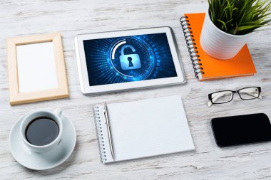 Ofis eşyalarıyla iş yeri ve ekranda asma kilit simgeleri olan tablet