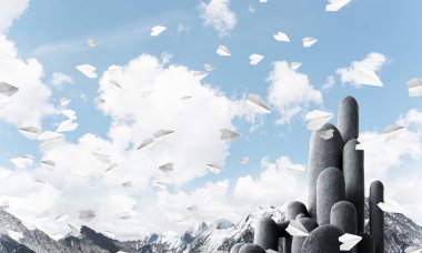 Açık havada, arka planda güzel manzarası olan uçan kağıt uçaklar arasında yer alan yüksek ve büyük taş sütunların resmi. Duvar kağıdı, telif alanı olan arkaplan.