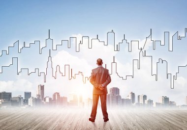 İşadamı arkasını dönüp modern iş merkezinin siluetine bakıyor.