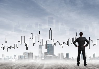 İşadamı arkasını dönüp modern iş merkezinin siluetine bakıyor.