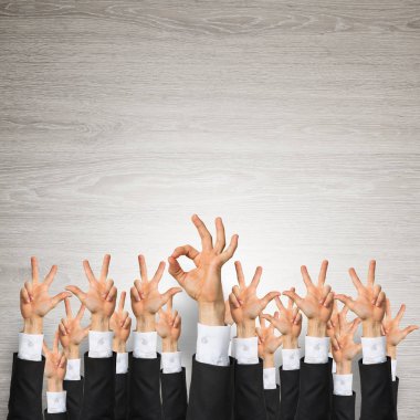 Bir grup iş adamı ahşap arka planda jestler gösteriyor.