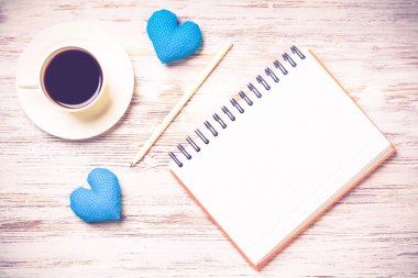 Kahve fincanı not defteri kalem ve ahşap yüzeyde iki kalp