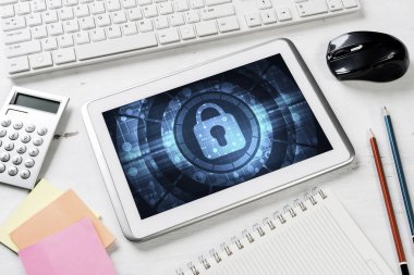 Ofis eşyalarıyla iş yeri ve ekranda asma kilit simgesi olan tablet