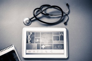 Gri yüzeyde beyaz tablet ve doktor araçları
